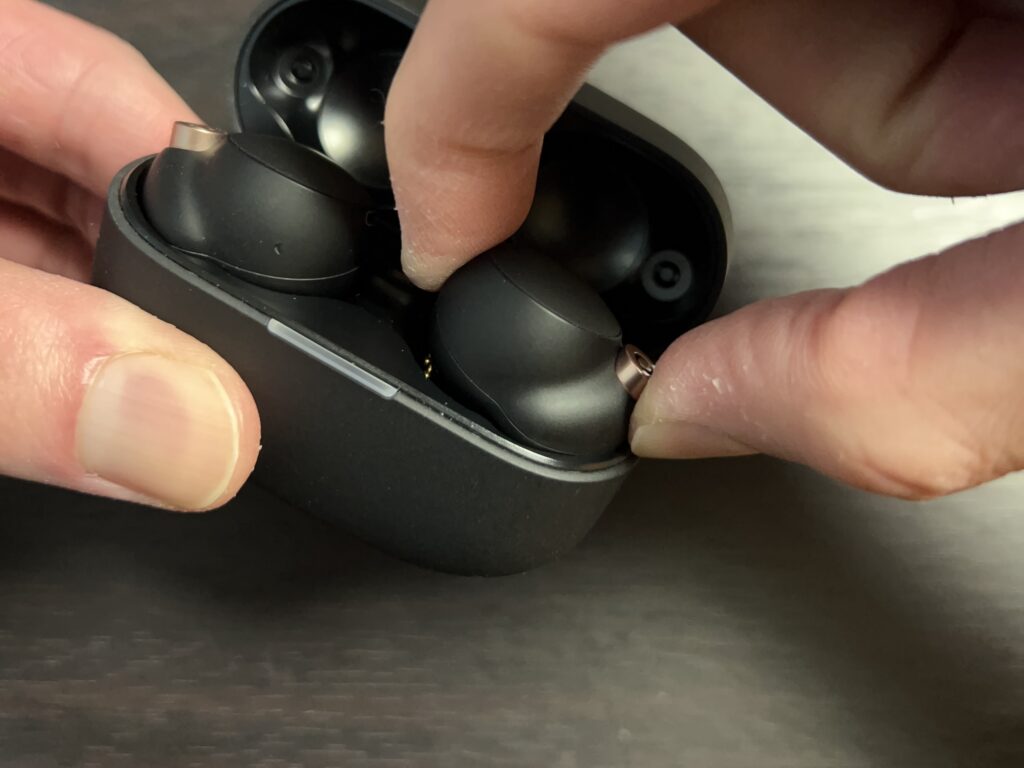 WF-1000XM4 イヤホンを指でつまんで充電ケースから取り出している様子。マット素材で滑りやすい場面もあることを示す。