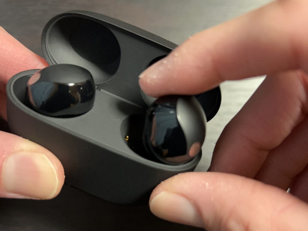 WF-1000XM5 イヤホンを指一本で充電ケースから取り出している様子。小型化と形状変更により取り出しやすくなったことが分かる。