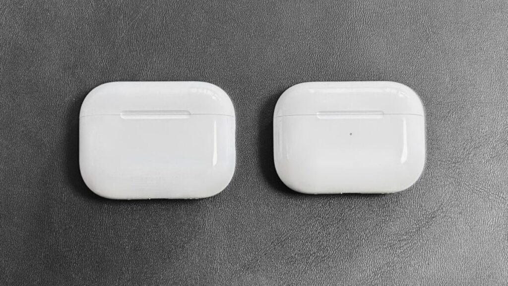 AirPods Pro 3(左)とAirPods Pro 2(右)の充電ケース正面比較(ランプ消灯時)。ランプ穴の有無による外観の違い