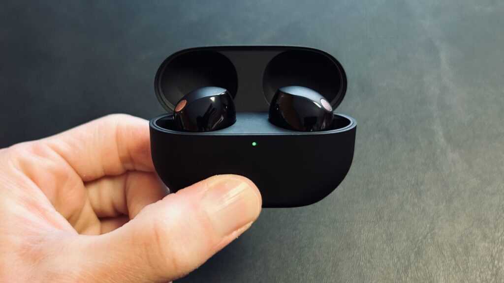 WF-1000XM5 を充電ケースに収納した状態で、LED が点灯している実写写真。高級感とコンパクトさを表現。