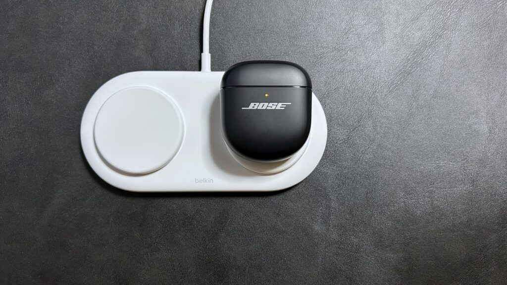 BOSE QuietComfort Ultra Earbuds 第2世代の充電ケースをワイヤレス充電パッドに置いた様子・充電ランプ点灯中