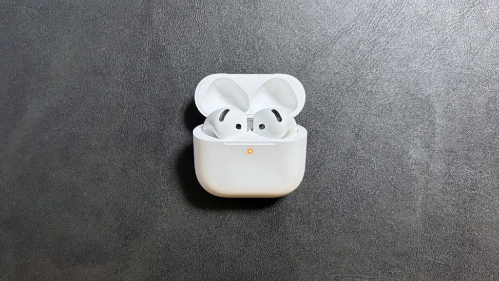 AirPods 5の充電ケースにAirPods 4のイヤホンを入れた状態。ケースのランプがオレンジ色に点滅して取り違えを知らせている